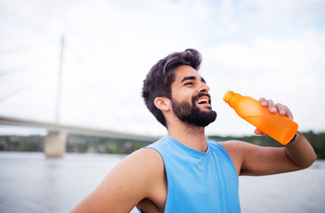 Take a break.Handsome fitness man holding water bottle