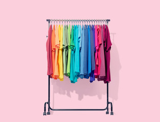 mobile rack with color clothes on light pink background. file contains a path to isolation.