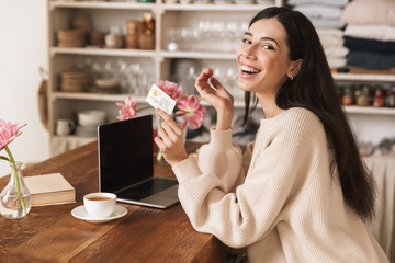 Canvas Print - Photo of beautiful brunette woman 20s using laptop computer in kitchen at home