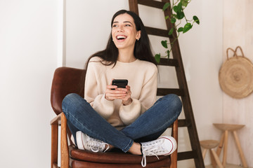 Poster - Photo of young cauasian woman 20s using cell phone while sitting on chair