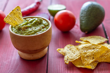 Guacamole and chips nachos. Red background. Mexican cuisine.