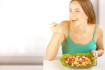 Young woman with bowl of salad on healthy food background