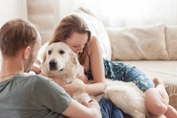 Young lovers newlyweds relaxing together on the sofa in the living room of their country house next to the dog lying on the floor during the weekend