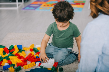 Wall Mural - cropped view of mother and son playing with blocks on carpet in living room