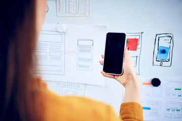 Close-up of businesswoman holding smartphone at whiteboard in office