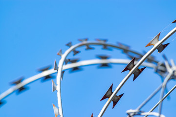 Barbed wire of a fence against blue sky