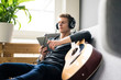 © Westend61 - Relaxed young man with tablet and guitar listening to music with headphones