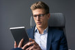 © Westend61 - Young businessman sitting on office chair using tablet