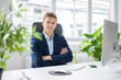 © Westend61 - Portrait of confident young businessman sitting at desk in office