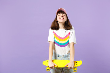 Wall Mural - Portrait of happy teen girl in vivid clothes hold yellow skateboard, keeping eyes closed isolated on violet pastel background in studio. People sincere emotions, lifestyle concept. Mock up copy space.