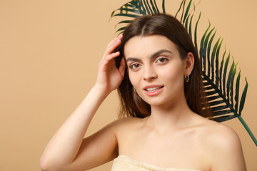 Wall Mural - Close up brunette half naked woman 20s with perfect skin, nude make up palm leaf isolated on beige pastel wall background, studio portrait. Health care cosmetic procedures concept. Mock up copy space.