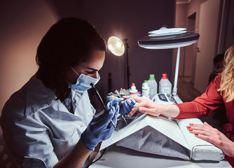 Manicure procedure in a beauty salon - Beautician making long transparent artificial nails to a female client