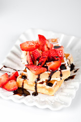 Wall Mural - Belgium waffers with sugar powder, strawberries and chocolate on ceramic plate on white table.