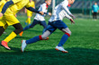 © Natali - Boys at white yellow sportswear run, dribble, attack on football field. Young Soccer players with ball on green grass. Training, football, active lifestyle for kids