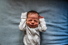 Newborn Laying Down And Making Funny Face With Hands Up