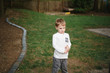 © Cavan Images - portrait of a small boy with a messy face stands in his backyard
