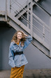 © Cavan Images - Young beautiful curly woman stands on the street in a denim jacket