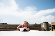 Toddler Boy Eats Ice Cream In Front Of A Blue Sky In Oxford, Maryland