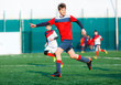 © Natali - Boys at white red sportswear run, dribble, attack on football field. Young Soccer players with ball on green grass. Training, football, active lifestyle for kids