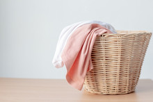 White And Pink Clothes In Laundry Basket With Copy Space On Table..