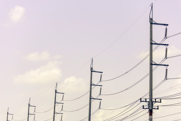 Row of electricity pole on green nature road in Thailand, Transmission line of electricity to rural, High voltage electricity pole on bright sky clouds background, electricity transmission pylon.