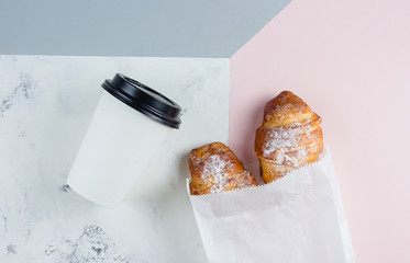 Fresh Croissants with coffee to go in a paper cup on tricolor background. Take away breakfast. Minimalism concept. Flat lay, place fo text