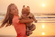 Happy blonde woman with french bulldog on india goa beach at sunset