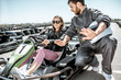 © rh2010 - Man in sportswear instructing young woman driver before racing on the go-karts on the track outdoors