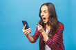 © denis_vermenko - Portrait of a furious young business woman yelling at mobile phone isolated over blue background.