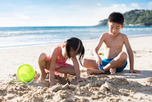 Two Children Playing With Sand On Beach