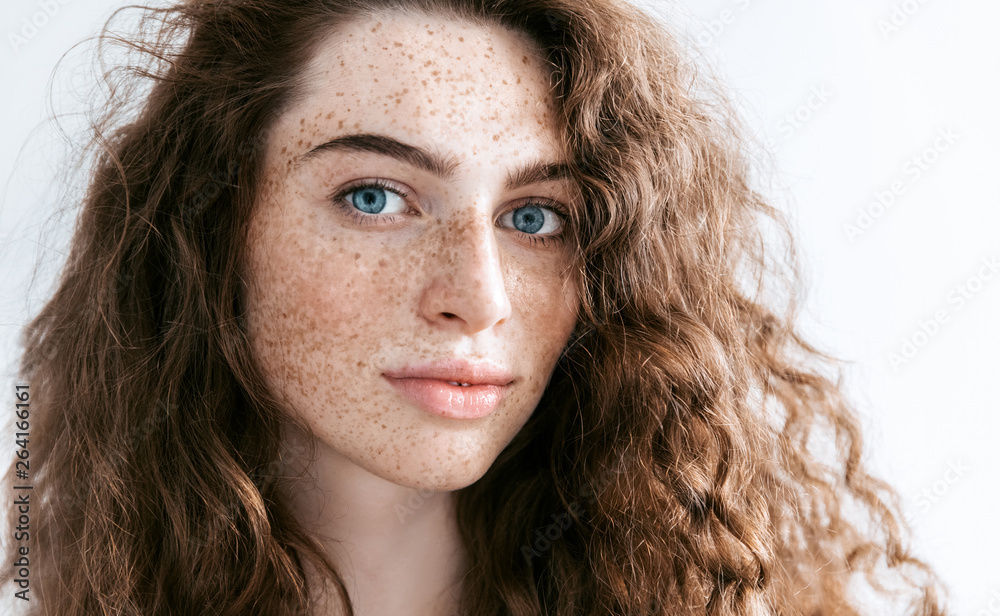 Beautiful Freckles young woman close up portrait. Attractive model with beautiful blue eyes and ginger curly hair - obrazy, fototapety, plakaty 