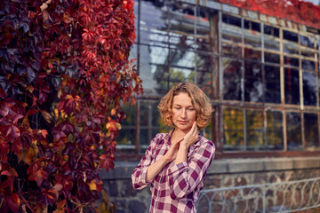 Cute woman on the background of the greenhouse in the autumn park
