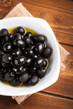 Fototapeta Kuchnia - Black olives on wooden background