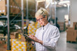 © Dusan Petkovic - Young Caucasian blonde woman in white uniform using tablet in warehouse.