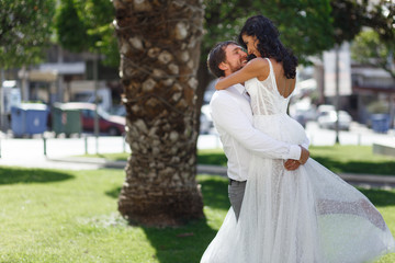 Wall Mural - Beautiful wedding couple embracing in public park in Greece, looking at each other, in love. Love in air concept.