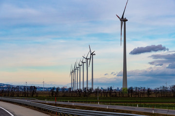 Windmills in a row at the evening with road in the foreground