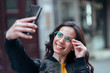 © bnenin - Headshot of brunette girl in eyeglasses taking selfie in the street.