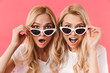 Shocked blonde twins take off sunglasses and looking at camera