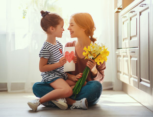 Wall Mural - happy mother's day! child daughter gives mother a bouquet of flowers to narcissus and gift.