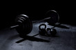 BACK LIT 365 pound weight on barbell with kettle bells on floor with dramatic light in gym