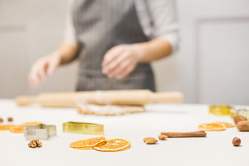 Wall Mural - Young pretty woman prepares the dough and bakes gingerbread and cookies in the kitchen. Merry Christmas and Happy New Year.