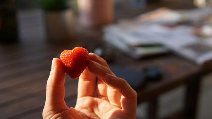 Wall Mural - Holding a heart-shaped strawberry