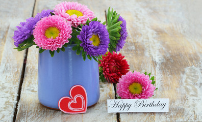 Wall Mural - happy birthday card with colorful pink daisies in blue vase on rustic wood
