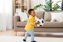 Childhood, Kids And People Concept - Lovely African American Baby Boy Playing With Soccer Ball On Floor At Home