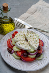 Wall Mural - Traditional greek salad made with fresh cucumber, tomato, paprika, red onion, kalamata olives, white salted feta cheese with oregano served with olive oil