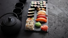 Assortment Of Different Kinds Of Sushi Rolls Placed On Black Stone Board