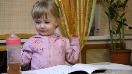 the little girl sitting at a table and draws in the album