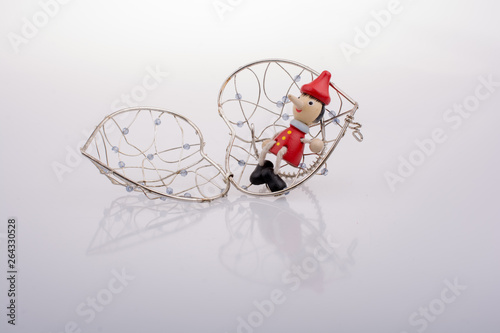 Pinocchio doll sitting on  a heart shaped cage