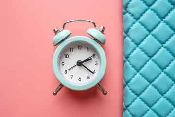 Blue analog metal alarm clock on stylish blue-pink background. Concept of time in pastel colors