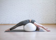 © junky_jess - Woman stretching back and spine using big fitness ball in pilates studio, loft background